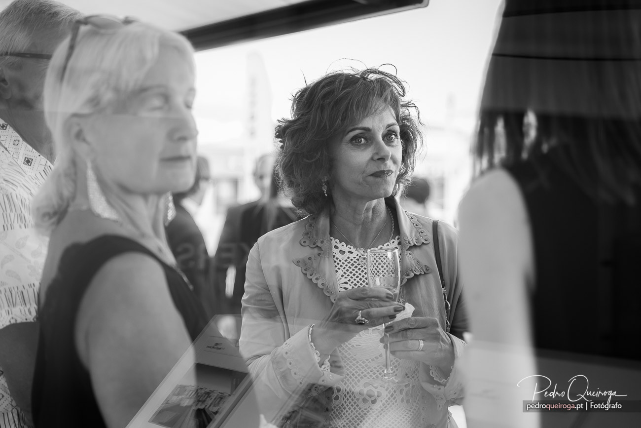 Mulher elegante segura taça de vinho enquanto conversa durante evento social, captada a preto e branco