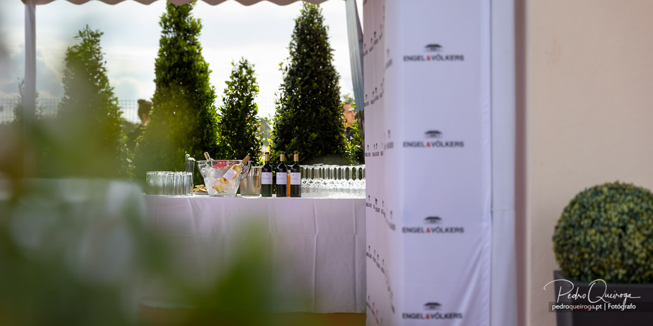 Mesa de bar elegante com champanhe e copos, capturada por Pedro Queiroga em evento ao ar livre