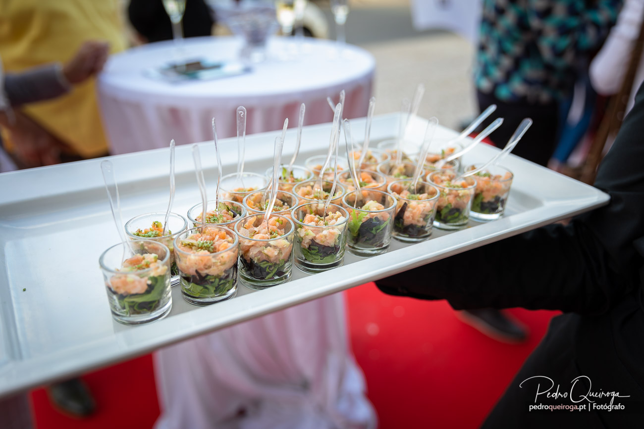 Tabuleiro com copos de aperitivo de salmão e alface servidos com palitos em evento social elegante