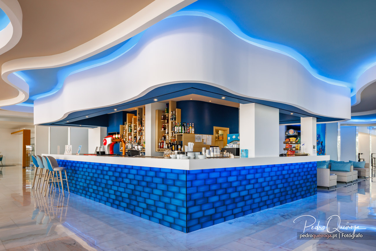 Bar moderno com revestimento azul texturizado e arquitetura fluida em tons de azul e branco no teto