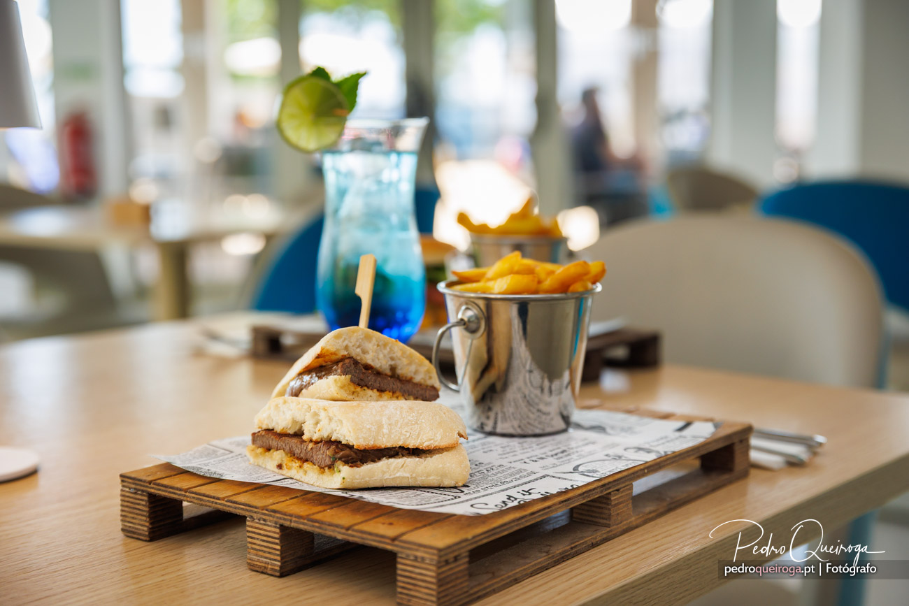 Hambúrguer artesanal servido em palete de madeira com batatas fritas e cocktail azul, fotografias de gastronomia premium