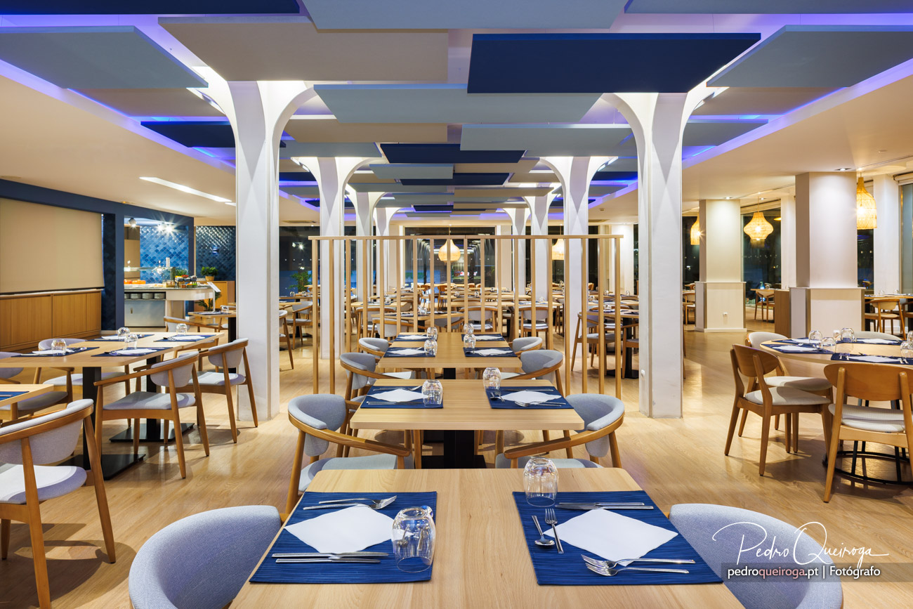 Restaurante moderno com arquitetura interior sofisticada, colunas brancas e iluminação LED azul no teto
