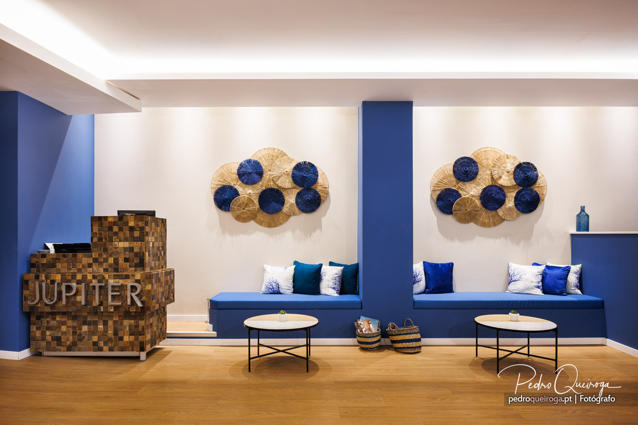 Sala de espera moderna da imobiliária Jupiter com bancos azuis, arte decorativa e balcão em madeira