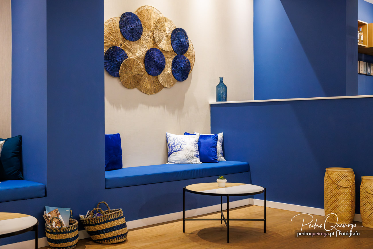 Sala de estar moderna com sofá azul royal, arte decorativa circular na parede e detalhes em dourado e azul