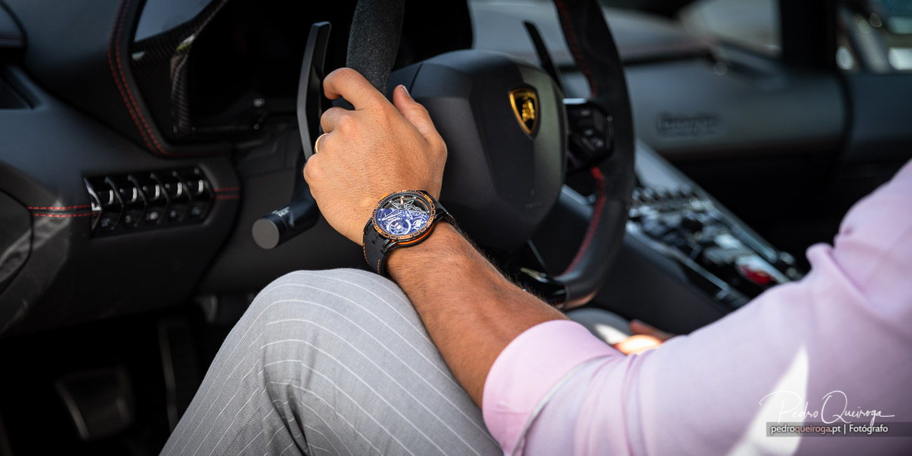 Mão ao volante de um Lamborghini exibe relógio sofisticado em contraste com interior desportivo elegante