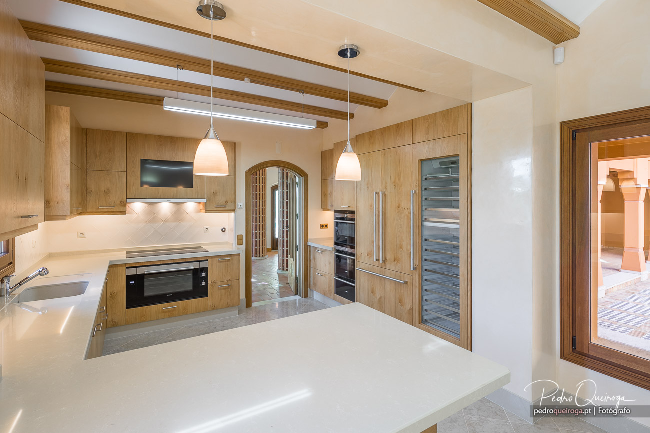 Cozinha moderna em madeira clara com vigas expostas, ilha central e decoração minimalista elegante