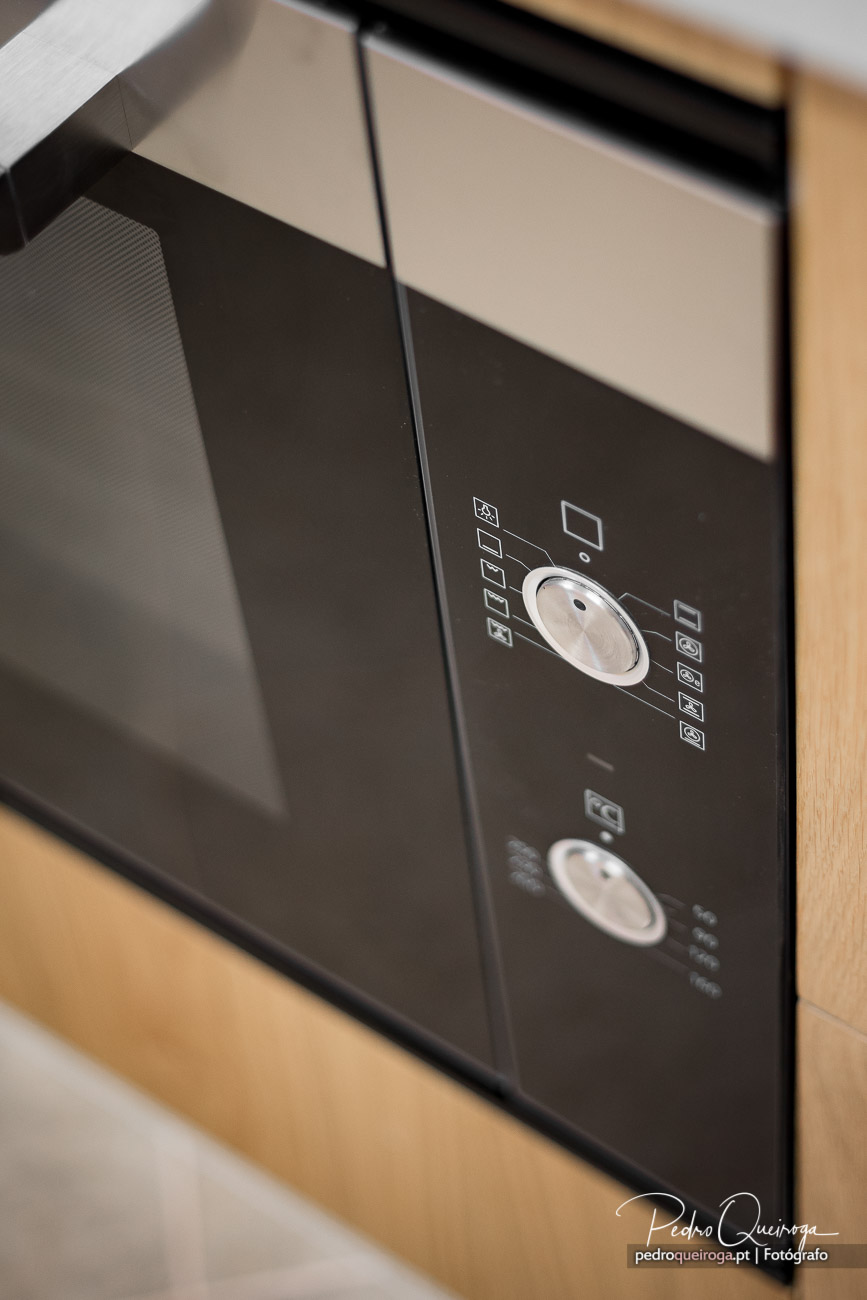 Painel de controlo moderno de forno encastrado em tons escuros com botões brancos e ícones minimalistas