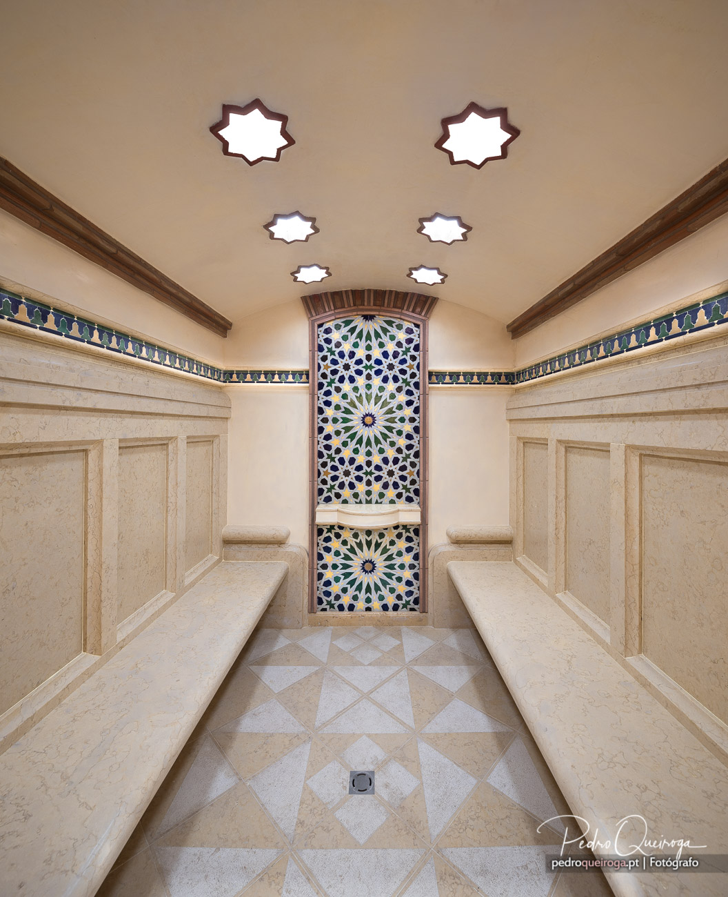 Interior de hammam com mosaicos geométricos coloridos, bancos em pedra e claraboias em estrela no Algarve