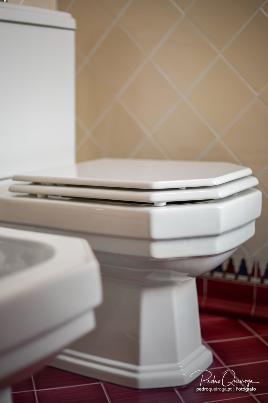 Sanita branca em casa de banho com azulejo bege em espinha, ideal para fotografia de imóveis