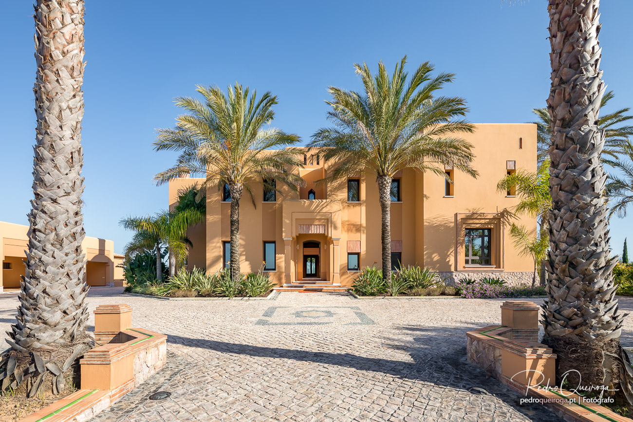 Moradia de luxo em tons ocre emoldurada por palmeiras, captada por fotógrafo de arquitetura no Algarve