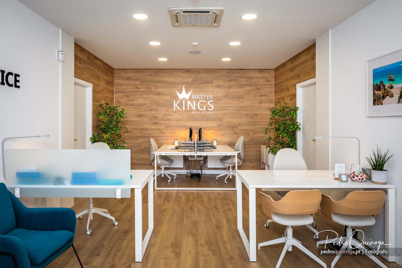 Escritório moderno com balcões brancos, parede em madeira com logótipo Master Kings e plantas decorativas