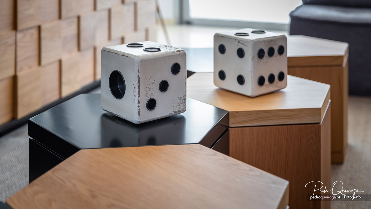 Dois dados decorativos em betão com acabamento industrial pousados sobre mesas em sala de estar moderna e minimalista.
