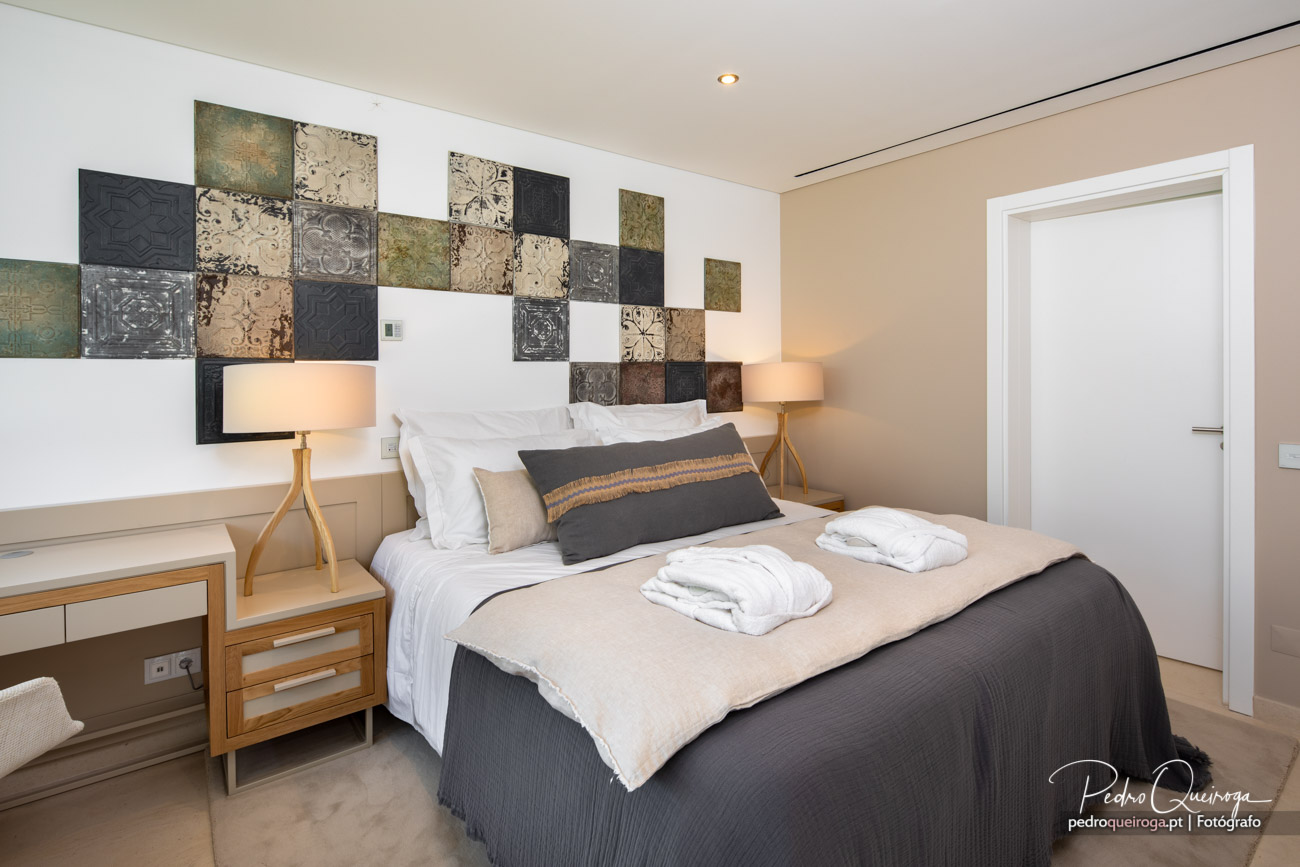 Quarto moderno com painel decorativo em mosaico, tons neutros e design elegante num alojamento no Algarve