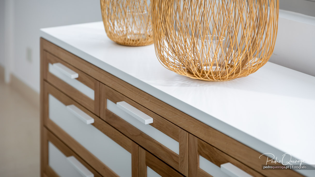 Cómoda moderna em madeira e branco com puxadores minimalistas e candeeiros decorativos em vime dourado