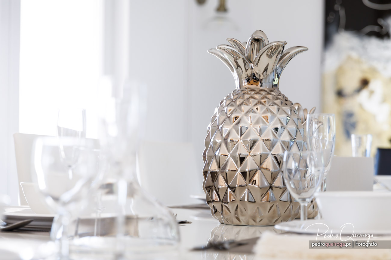 Ananás decorativo dourado brilhante sobre mesa com copos de cristal num ambiente elegante e luminoso