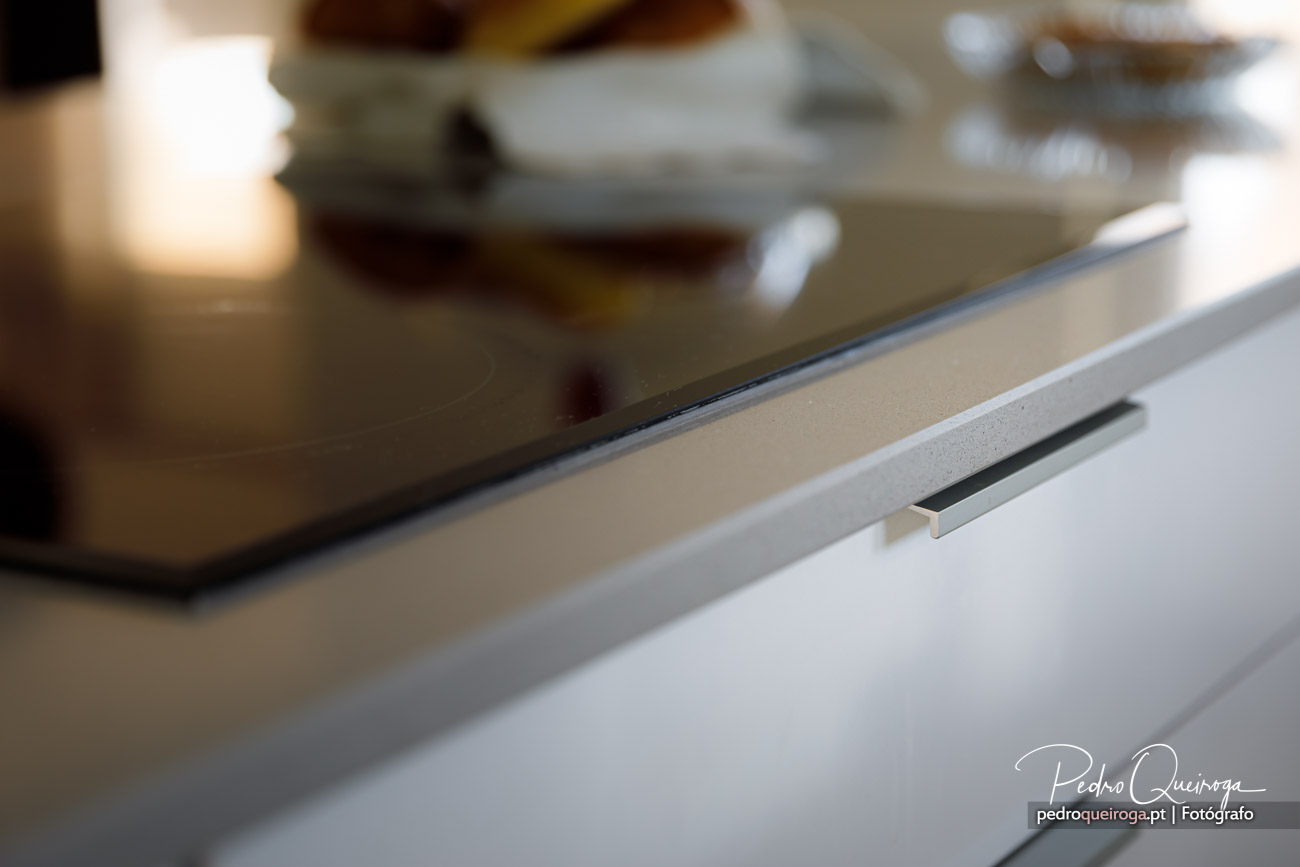 Detalhe de gaveta branca minimalista com puxador embutido em cozinha moderna e luminosa