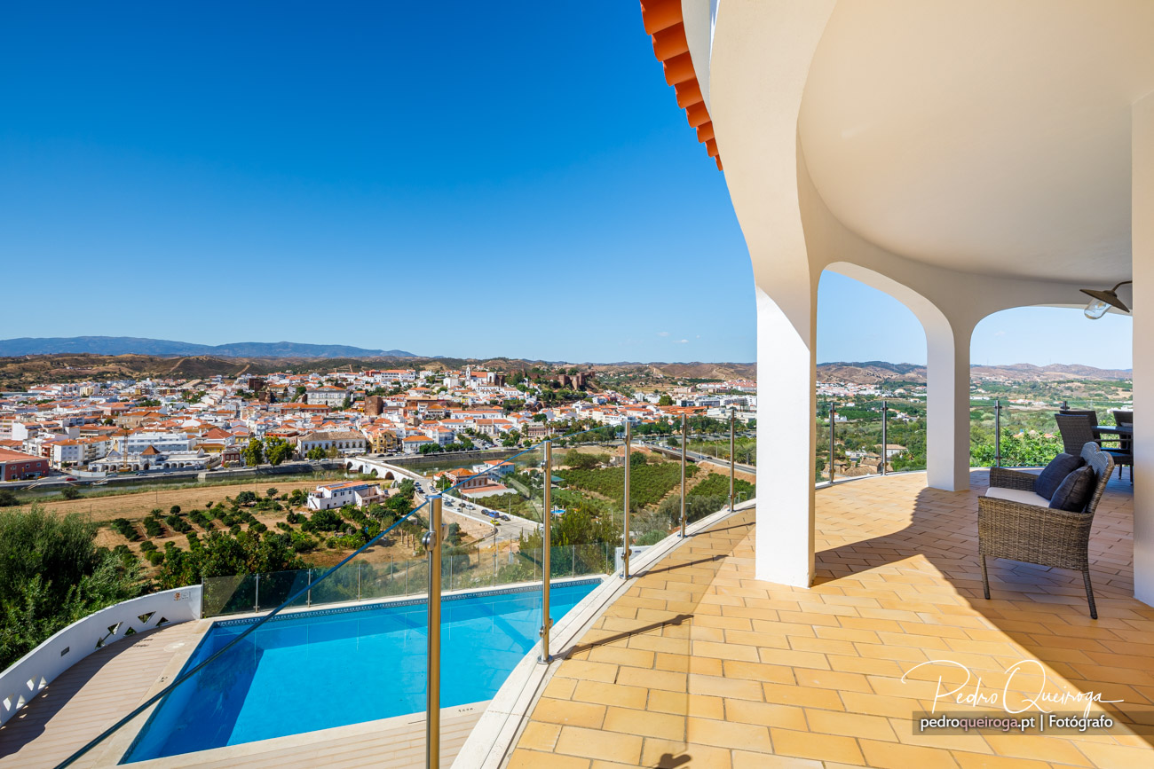 Terraço amplo com piscina e vista panorâmica sobre a vila algarvia sob céu azul intenso