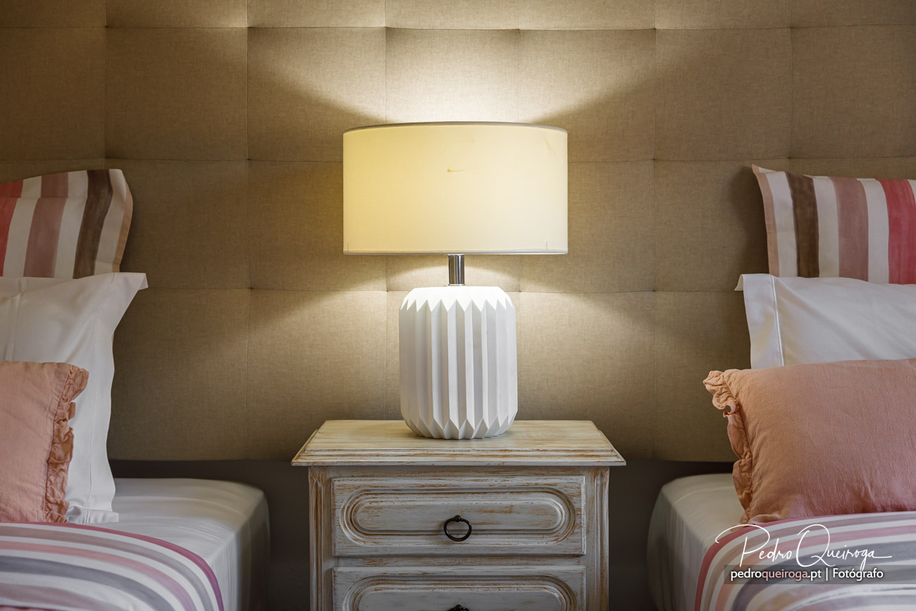 Quarto com duas camas, mesinha de cabeceira vintage e candeeiro branco moderno com parede estofada bege