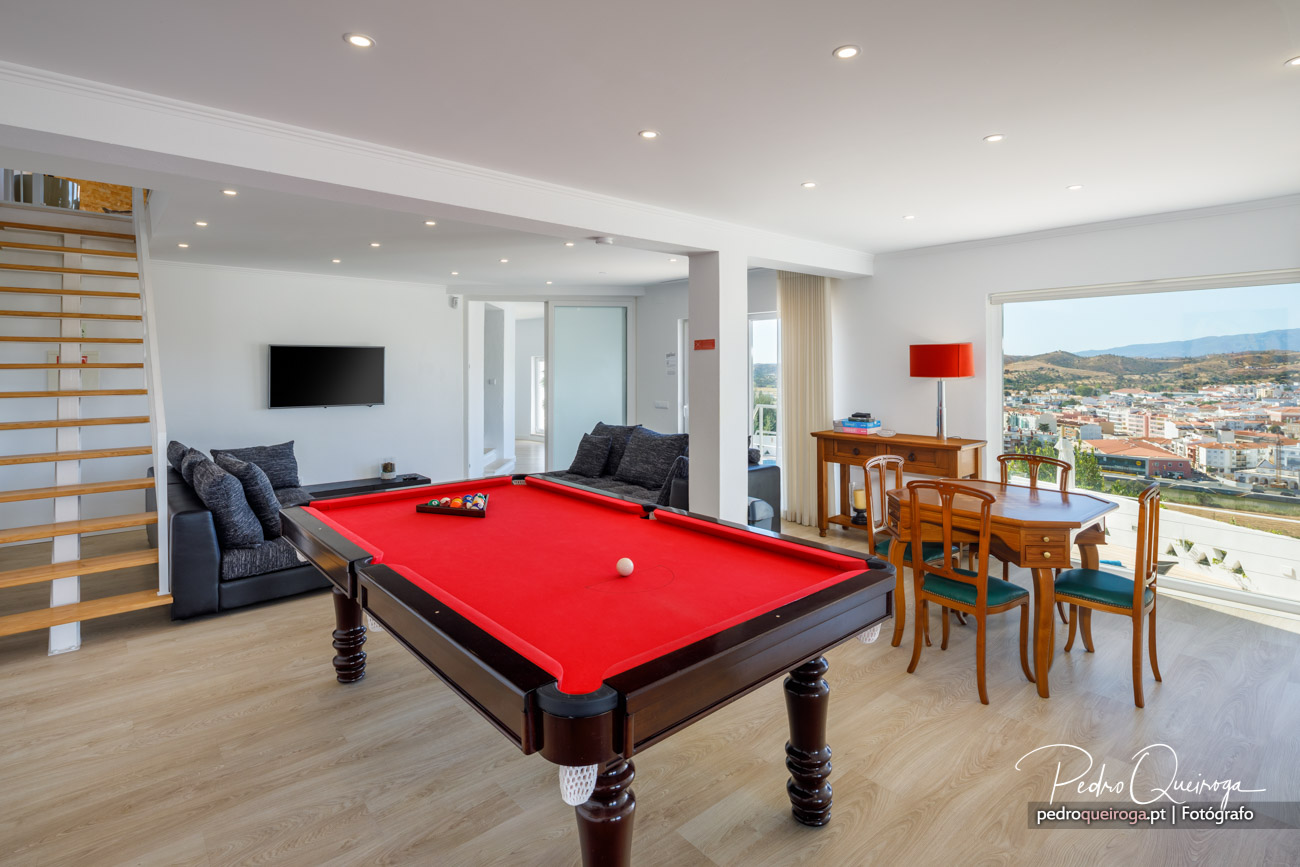 Sala ampla com mesa de bilhar vermelha, zona de estar e jantar, ideal para hotéis de luxo com vista panorâmica