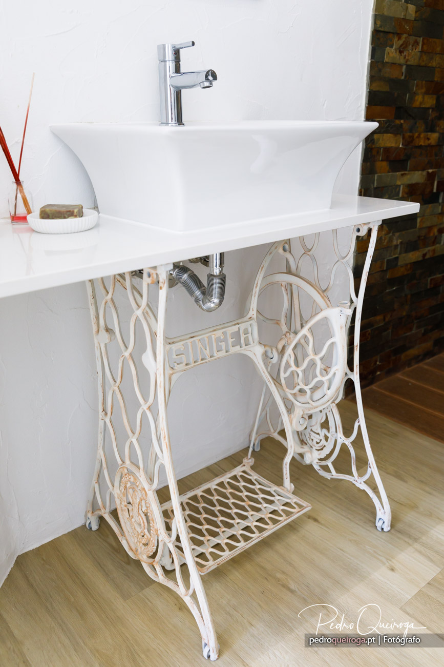 Lavatório moderno sobre base vintage de máquina de costura Singer branca, com parede em mosaico ao fundo