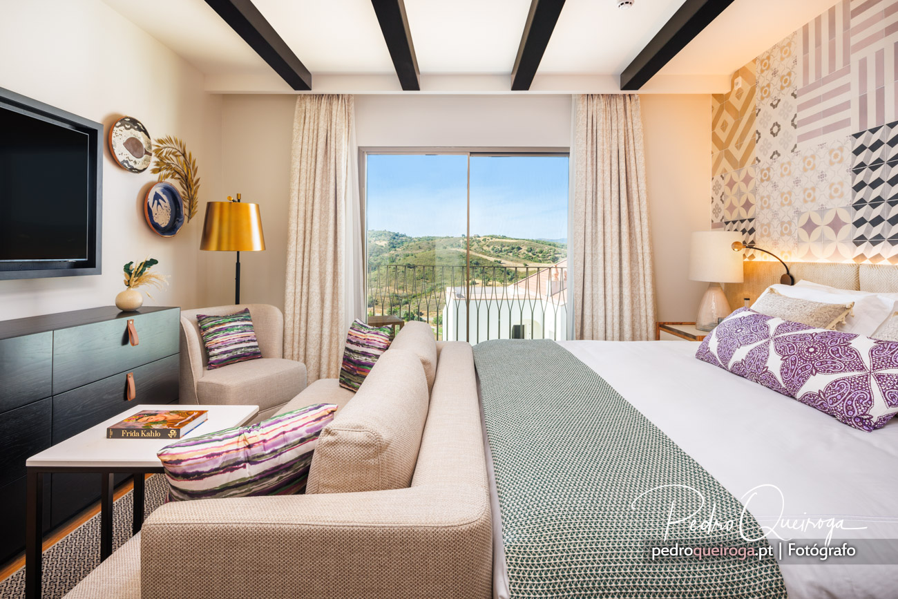 Quarto de casal com um sofá no rodapé da cama