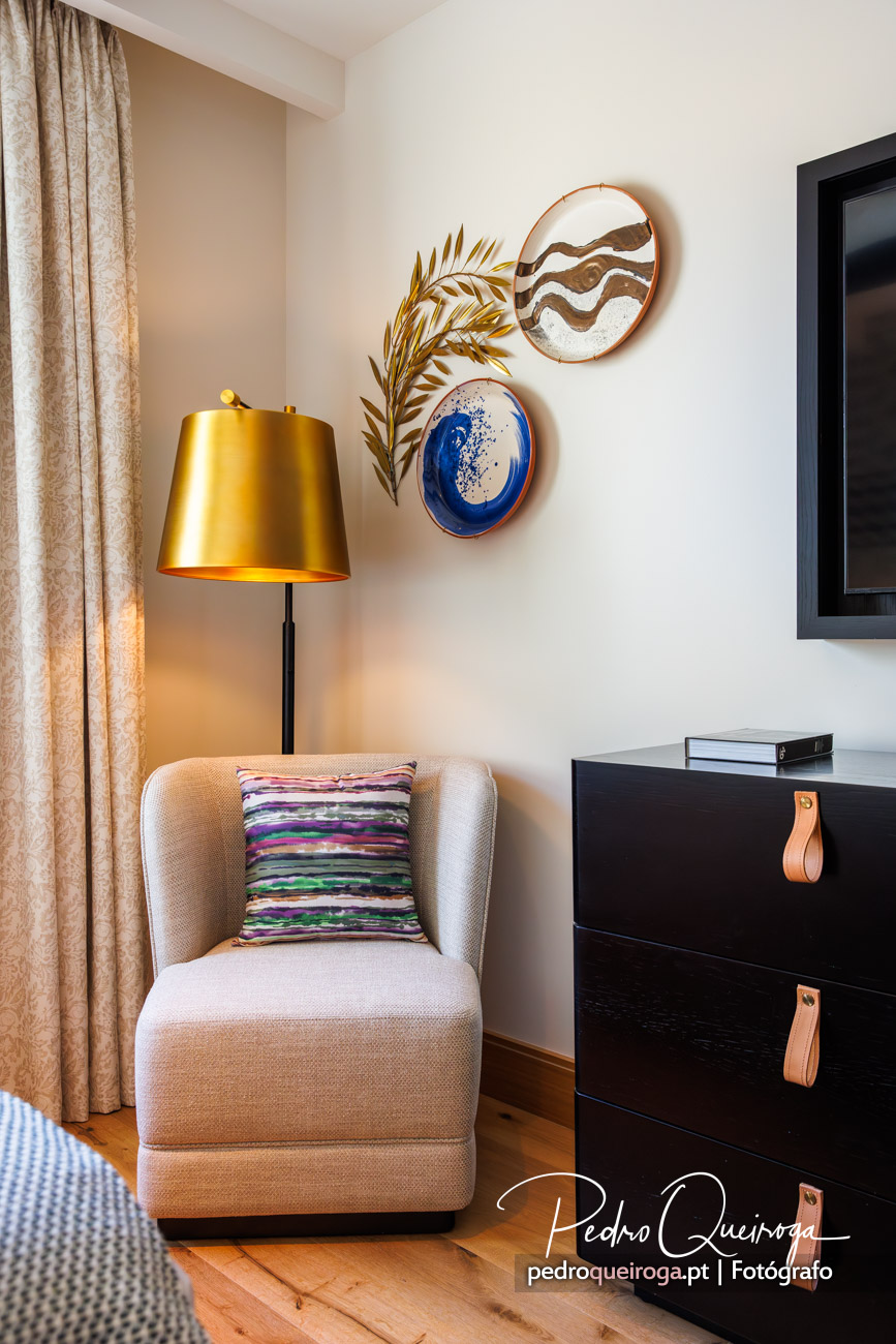 Fotografia de um canto do quarto com uma poltrona e um candeeiro de chão