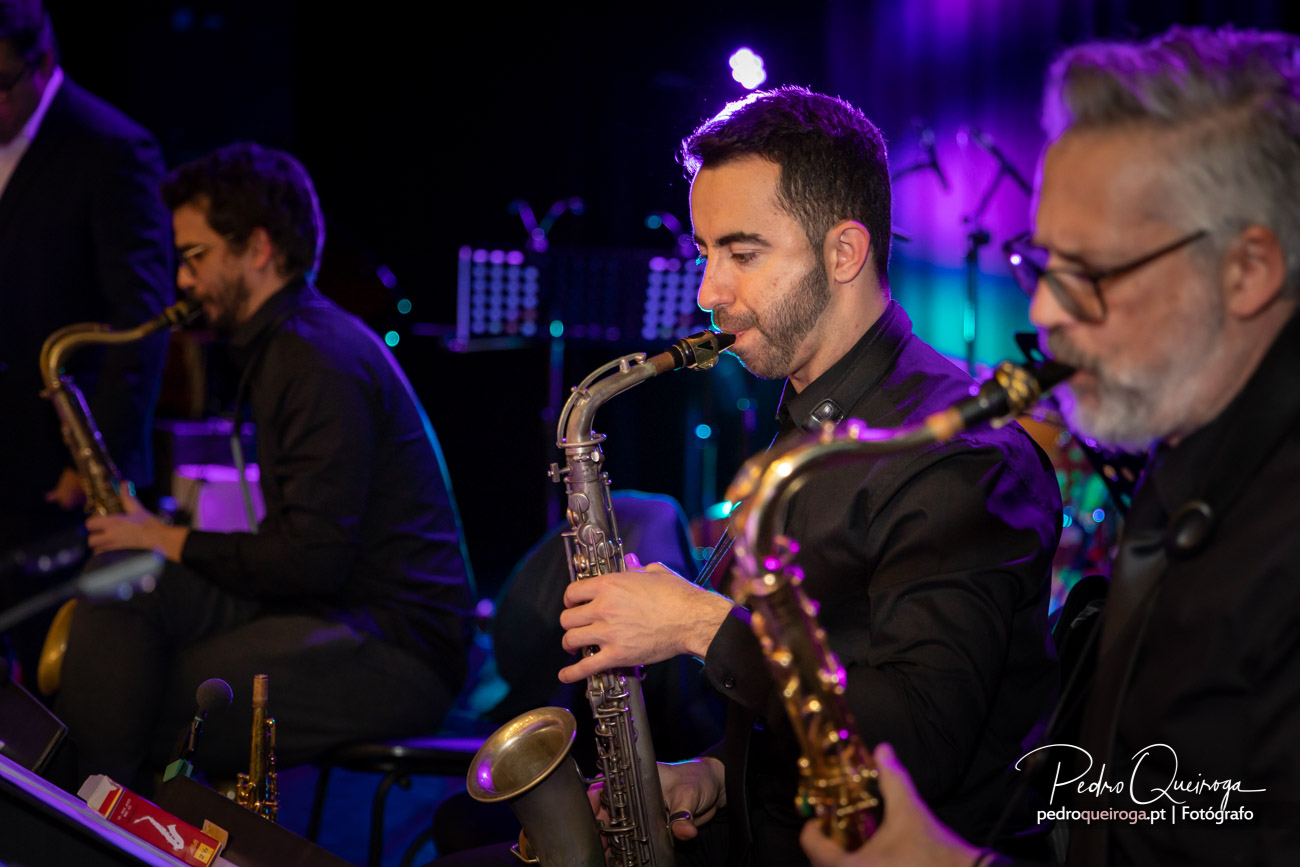 Saxofonistas em concerto com iluminação roxa e azul, criando uma arquitetura visual envolvente no palco