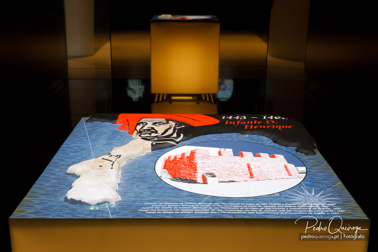 Painel interativo iluminado com ilustração histórica e texto sobre Infante D. Henrique em exposição museológica