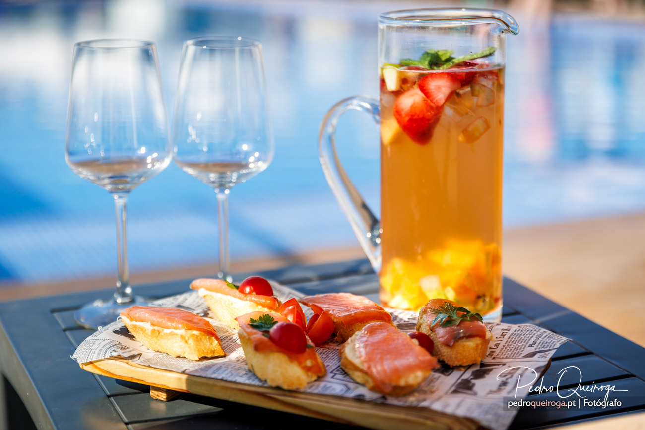 Taça de sangria refrescante com fruta e petiscos gourmet junto à piscina num dia de verão no Algarve