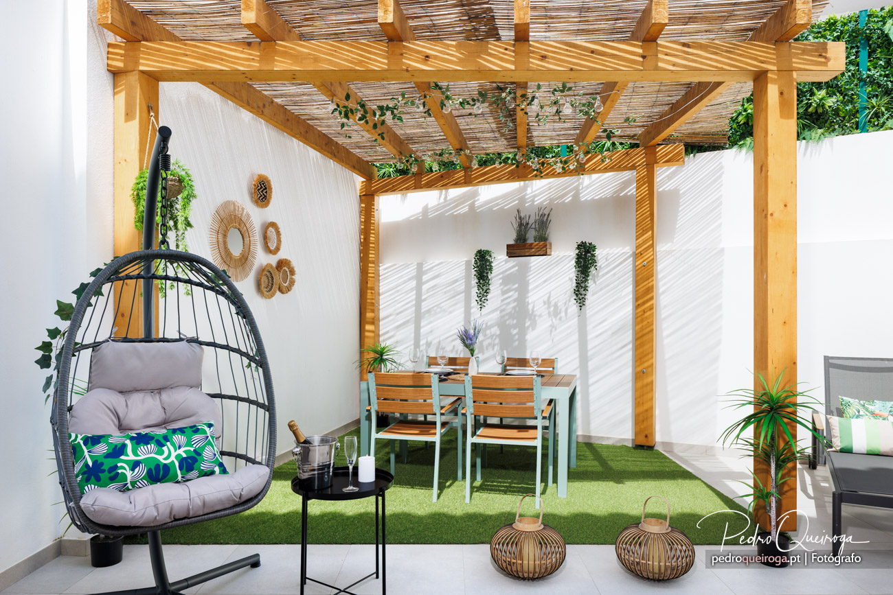 Terraço moderno com pérgula de madeira, cadeira suspensa e mesa de refeições em fotografia de interiores elegante