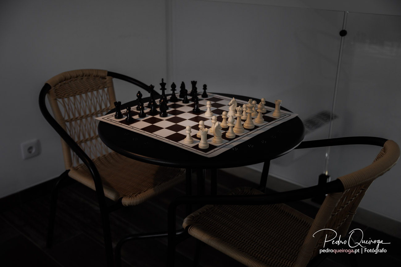 Tabuleiro de xadrez sobre mesa preta com cadeiras de vime, elemento perfeito de decoração num ambiente minimalista