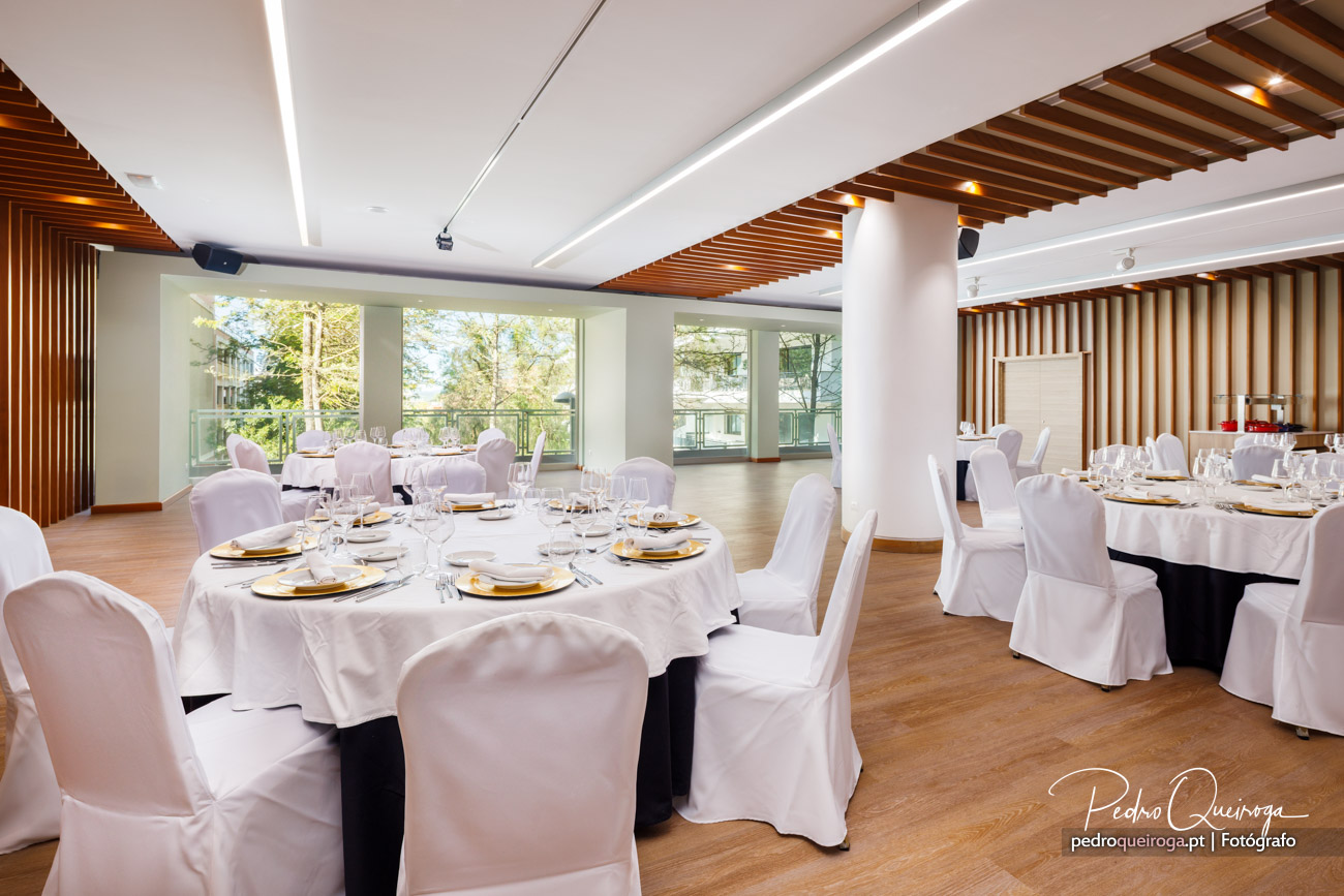 Salão de eventos elegante com mesas preparadas, arquitetura moderna em madeira e amplas janelas com luz natural