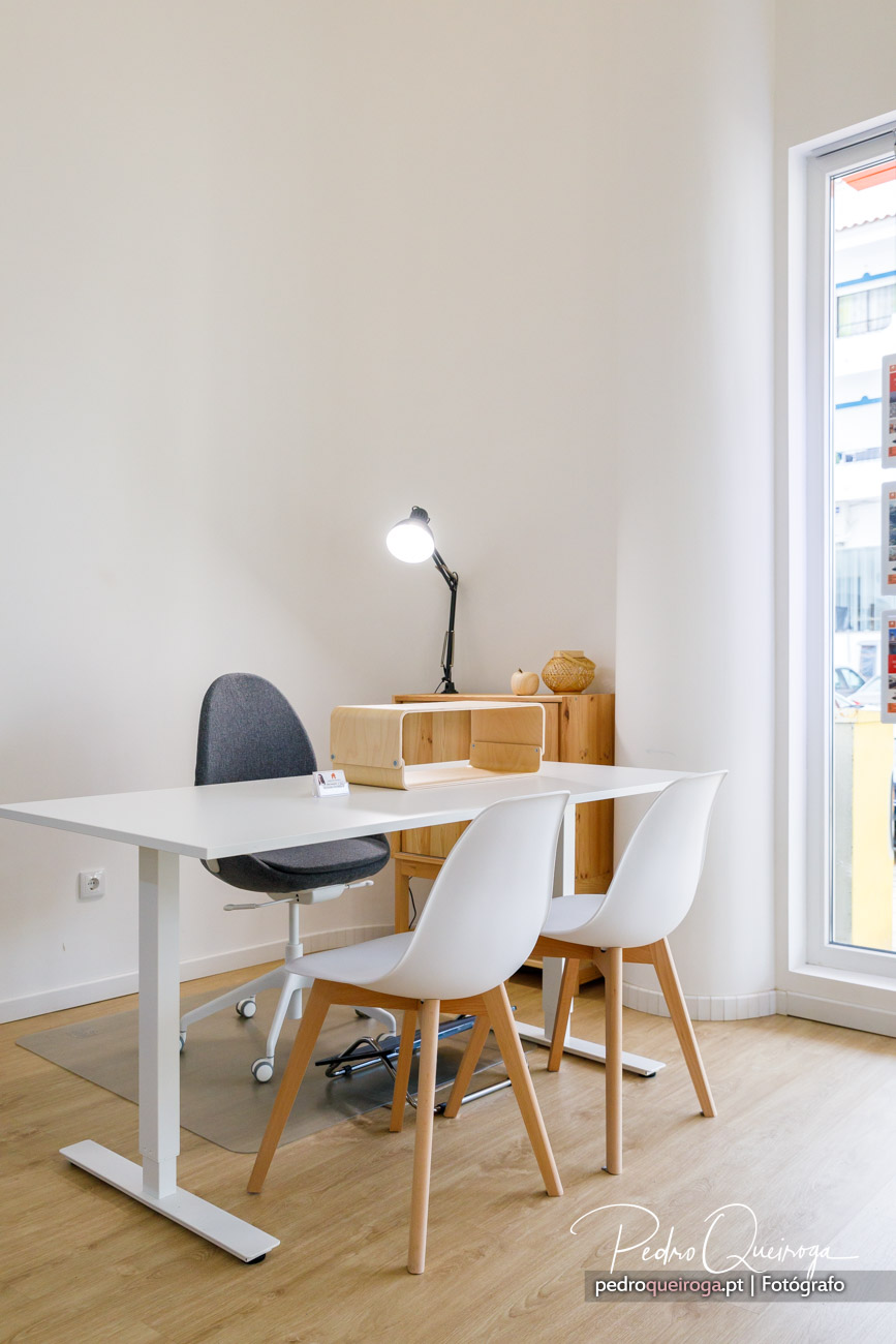 Escritório minimalista com mesa branca, cadeiras modernas e móvel em madeira com decoração natural e candeeiro preto