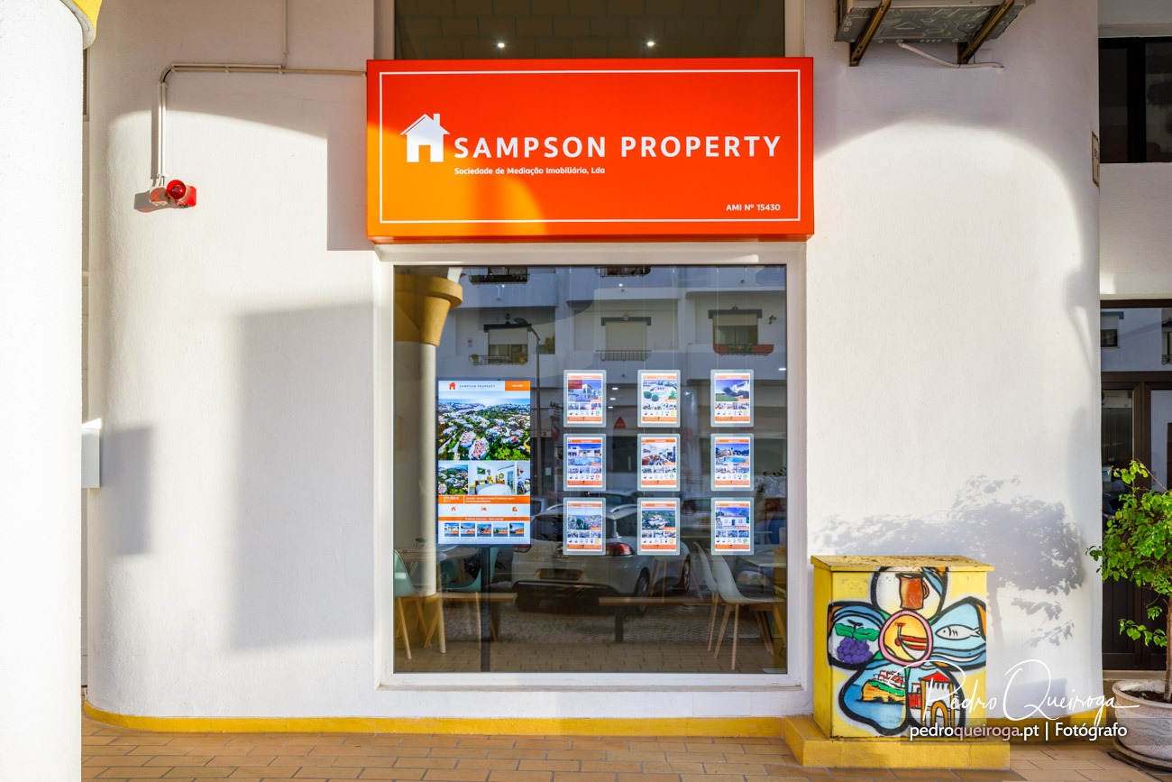 Montra da agência imobiliária Sampson Property com letreiro laranja e vitrine repleta de anúncios de imóveis