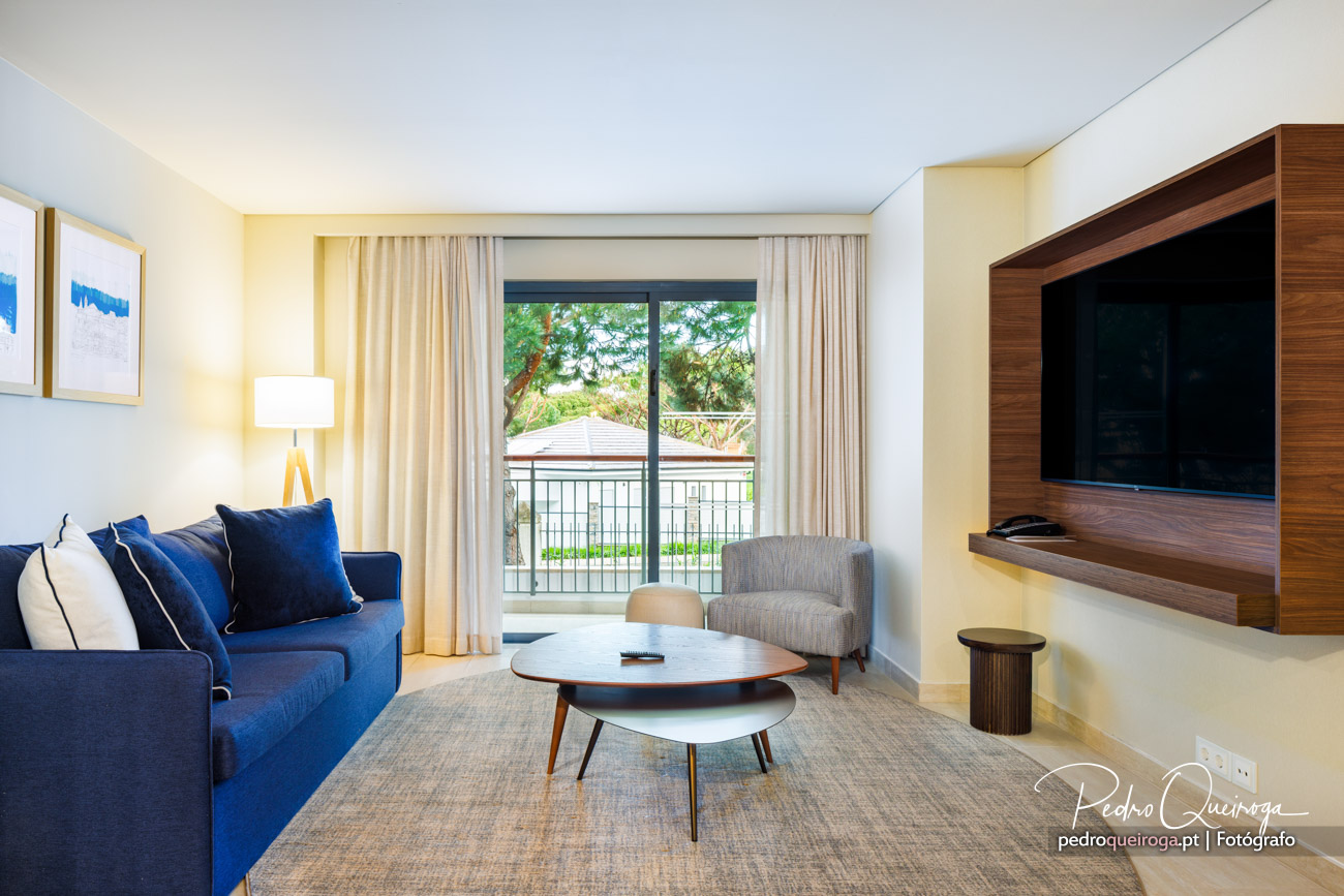 Sala de estar com TV, sofá, mesa central e cadeirão